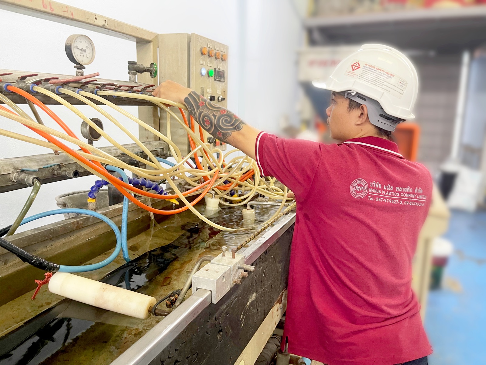 พนักงานบริษัท มนัส พลาสติก จำกัด กำลังควบคุมเครื่อง Plastic Extruder ที่รางหล่อเย็น